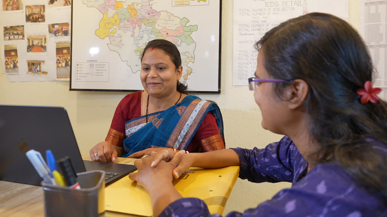 Two team members smiling over a laptop in the project office