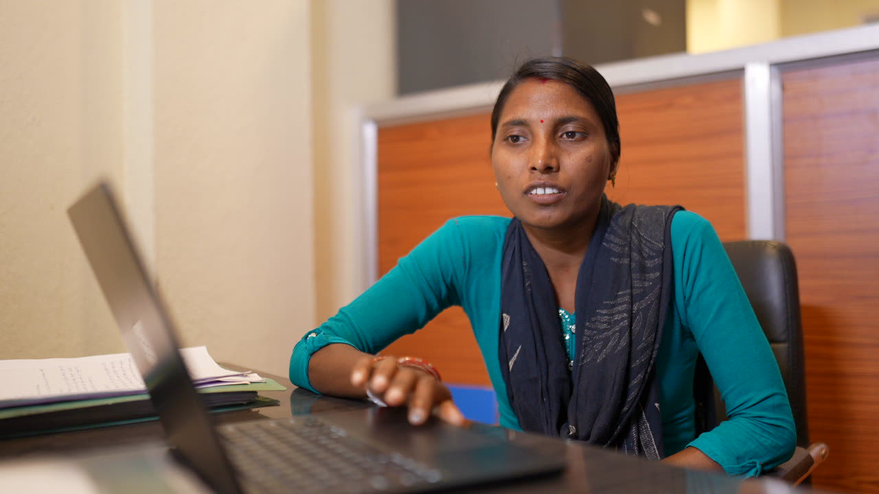 Team member in teal working on a laptop in the project office